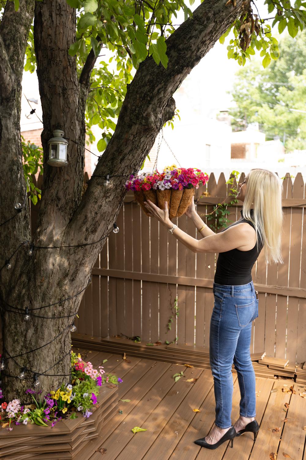 Rebecca Entwisle tending hanging flower baskets on a backyard deck in the Lehigh Valley